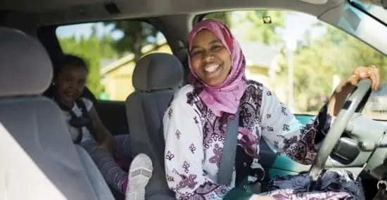 Người Phụ Nữ Lái Xe Mỉm Cười Với Đứa Trẻ Ngồi Ở Ghế Sau